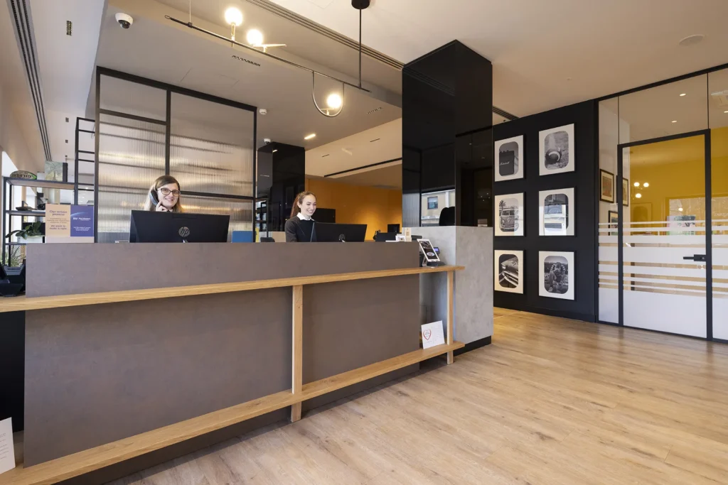 The image shows the reception area with two girls working at the front office.